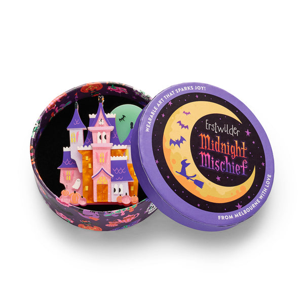 A colorful Halloween haunted house acrylic resin brooch with pink, purple, orange, and white sections, plus pumpkins, bats, and a ghost. Shown in illustrated round gift box packaging