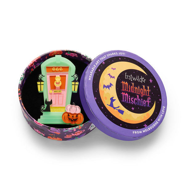 Halloween ghost house door acrylic resin brooch with a mint green frame, pink glittery door, orange number 666, black cat silhouette, yellow lanterns, and an orange jack-o'-lantern pumpkin, shown in illustrated round gift box packaging