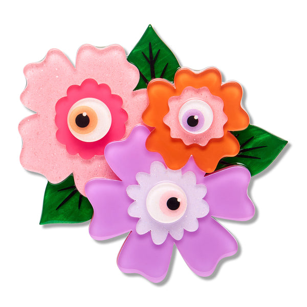 Acrylic resin brooch depicting three colorful flowers with eyeball centers, set against a plain white background.