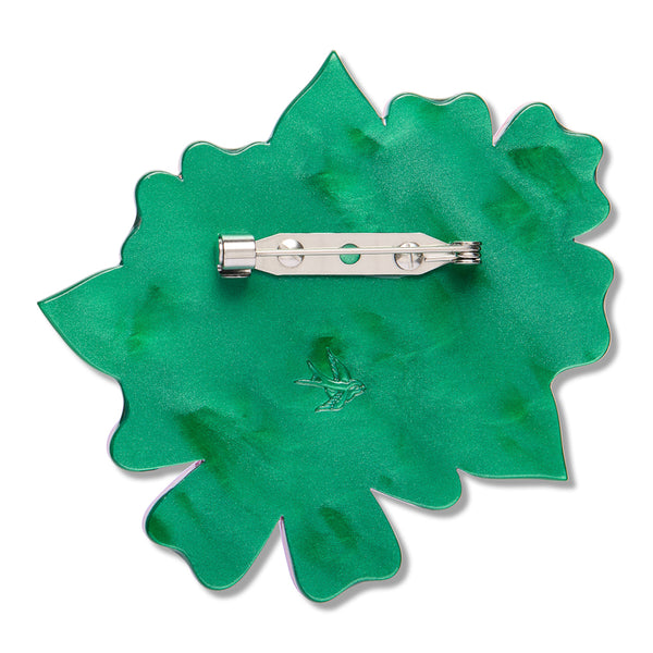 green resin back layer of a flower-shaped brooch with silver metal pin clasp fastener
