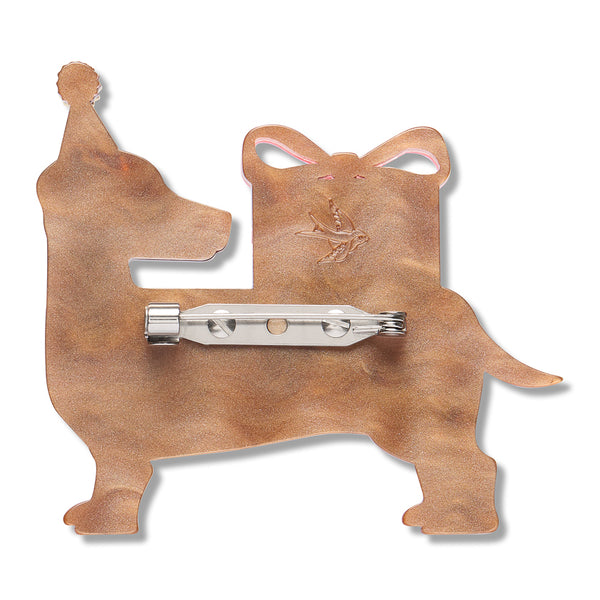 light brown acrylic resin back layer of a dog with a present on its back shaped brooch with silver metal pin clasp