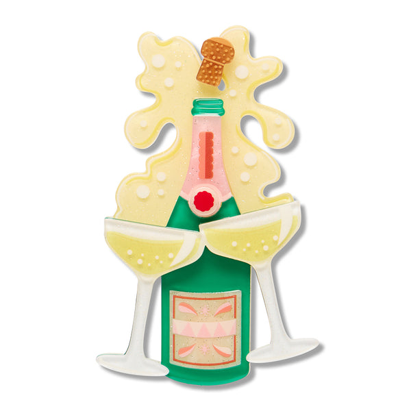 green acrylic resin champagne bottle brooch with a pink neck, two champagne glasses, and a yellow champagne splash behind it, isolated on a white background.