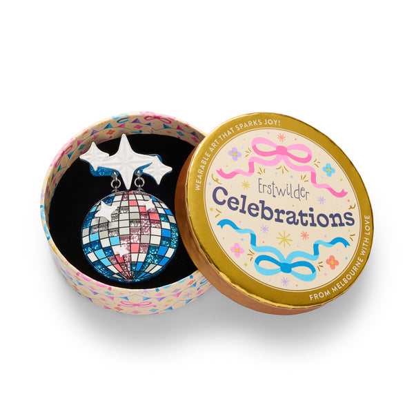 A disco ball shaped layered acrylic resin brooch in a checkered pattern of blue, pink, white, and silver glitter, hanging from two white star-shaped charms with blue glitter trim. Shown in illustrated round gift box packaging.