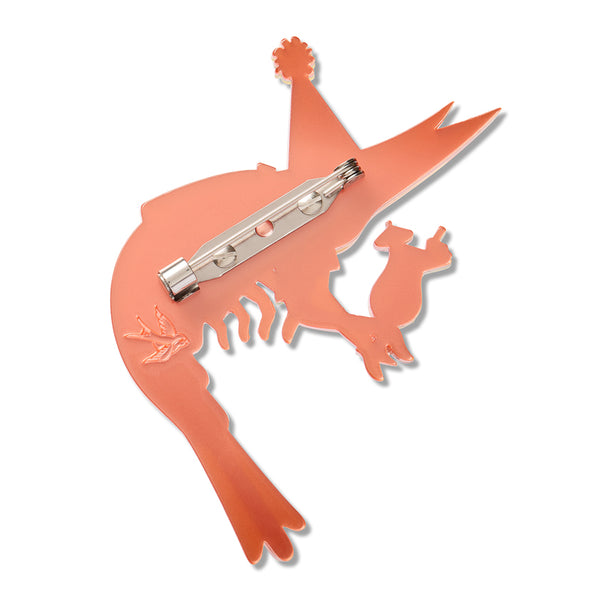 An orange acrylic resin shrimp-shaped brooch, showing the silver metal pin mechanism on the back, set against a plain white background.