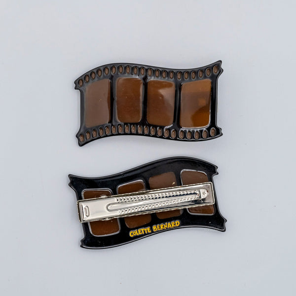 Translucent tawny brown acetate alligator style hair clip in the shape of a film strip shown front and back