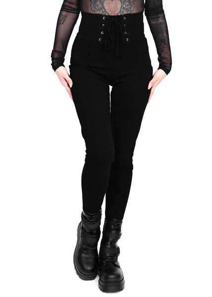 Model wearing black cotton modal blend leggings with high waistband and corset-style lace-up front detail. Shown from front in close up of leggings