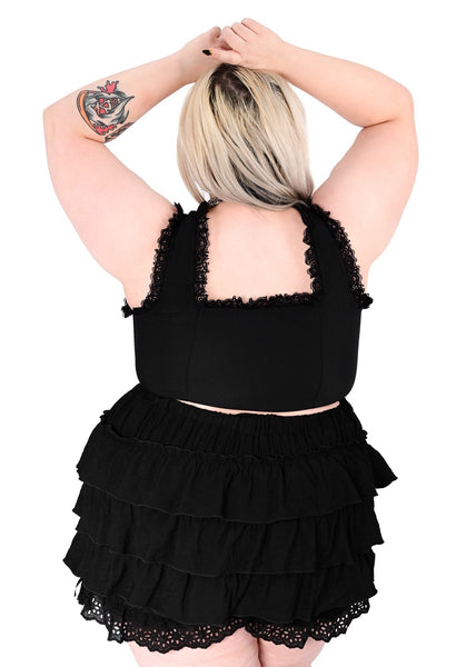 plus size model wearing black cotton twill corset top with metal hook and eye fasteners down length of bodice, flexible boning, and scoop neck with black floral lace trim. Shown from back