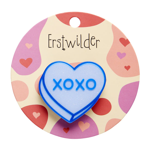 blue glitter resin candy heart brooch with 'XOXO' text, shown on branded backer card packaging 