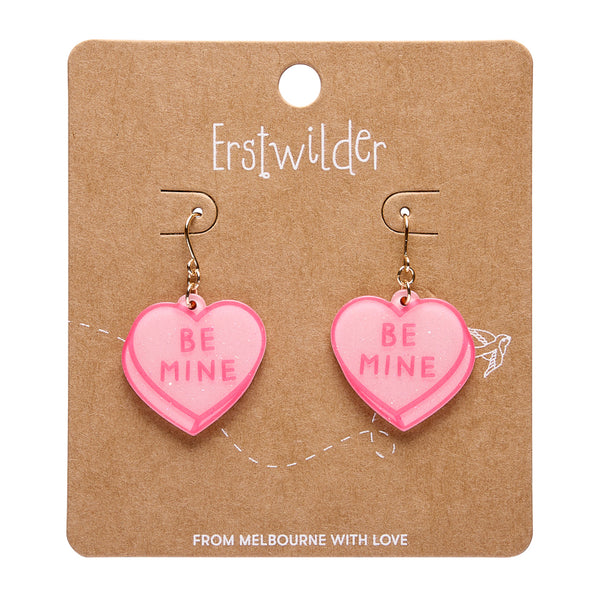 pair of "BE MINE" candy heart dangle earrings in pink glitter acrylic resin, shown on branded backer card packaging