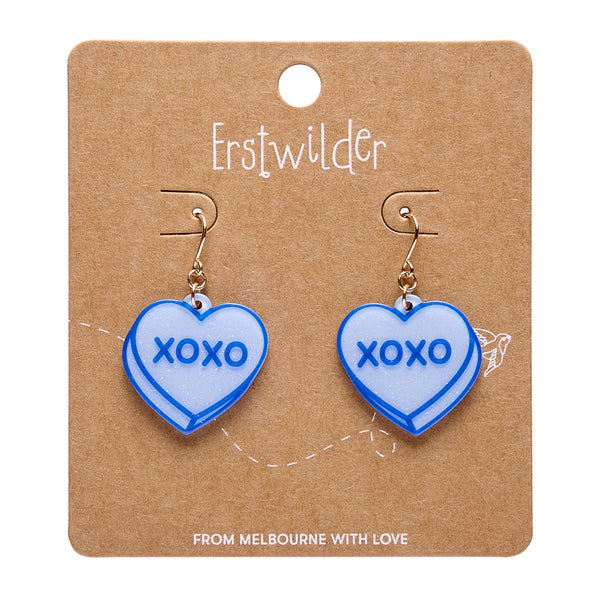pair of blue glitter resin candy heart dangle earrings with 'XOXO' text, shown on branded backer card packaging