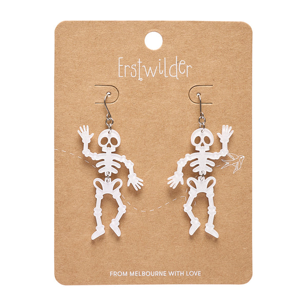 A pair of white skeleton-shaped dangle earrings displayed on a brown kraft card. The card has the brand name 'Erstwilder' printed at the top and 'FROM MELBOURNE WITH LOVE' at the bottom.