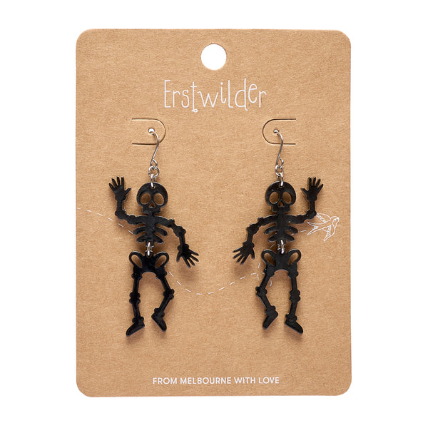 A pair of black skeleton drop earrings displayed on a brown kraft card. The card features the brand name 'Erstwilder' at the top and the text 'FROM MELBOURNE WITH LOVE' at the bottom.