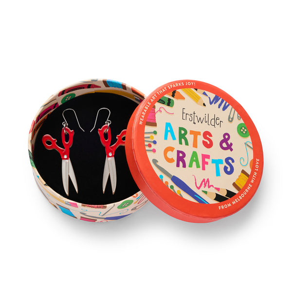 pair of red and metallic silver scissors-shaped earrings, shown in illustrated round box packaging