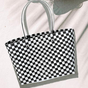 Black and white basket weave style plastic tote with clear plastic tube handle. Shown flat