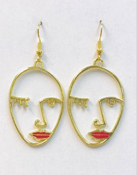 Gold metal dangle earrings with charms in the shape of abstract sketched faces with a winking eye and red enameled lips