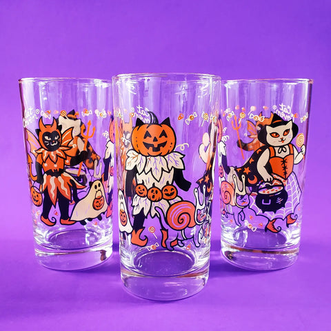 three drinking glasses screen printed with illustrations of cats wearing vintage inspired Halloween costumes