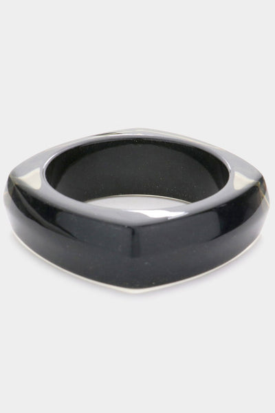 shiny square resin bangle with rounded sides in black with tiny flecks of silver and blue glitter and translucent top and bottom. Shown from side with translucent top showing