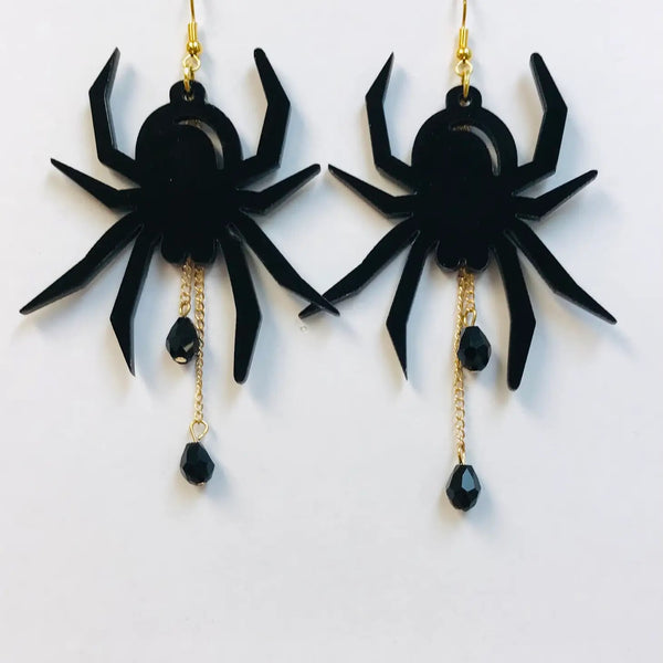 shiny black laser-cut acrylic spiders hanging upside down with dangling gold metal chains and faceted black beads hanging from the spider