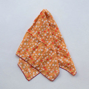 cotton scarf in orange with allover dainty floral print in red, white, brown, and green and finished with rich red embroidered scallop trim