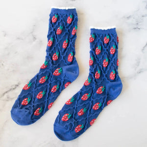 cotton knit socks in blue with a textured knit-in pattern of red strawberries and a matching wavy diamond pattern. Shown lying flat