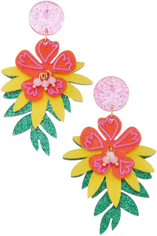 drop earrings featuring orangey-pink hibiscus flowers with bright pink detailing & pink bead centers linked to a pair of yellow and green glitter leaves- dangling from light pink glitter dot posts. 