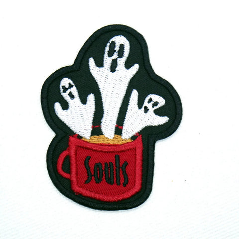 An embroidered patch of a trio of spooky yet friendly looking cartoony ghosts rising out of a cup of coffee labeled “Souls”