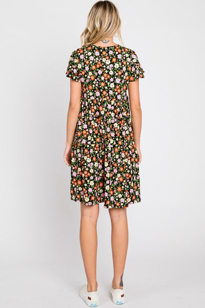 Knit dress in a red, pink, yellow, and green floral pattern on a black background. The dress has a shallow v-neck and short flutter sleeves with a gathered at the waist tiered skirt that ends just above the knee. Shown on a model from behind