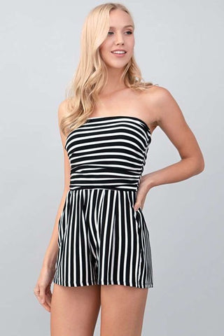 A model wearing a strapless black and white striped romper. It has slight ruching at the bodice and relaxed fit style high-waisted shorts.
