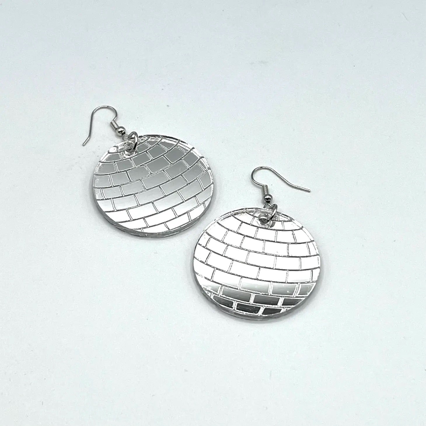 A pair of mirrored silver acrylic disco ball dangle earrings with silver metal fishhook hardware 