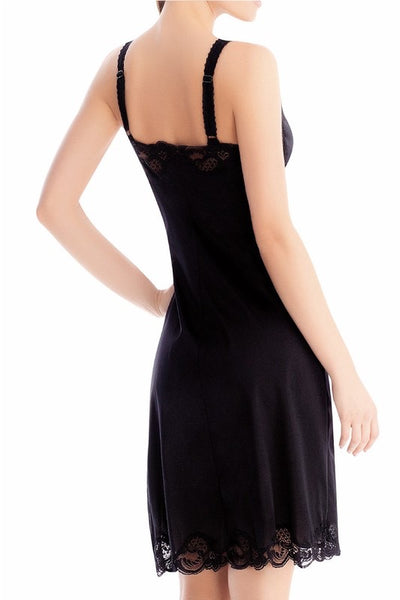  slinky and soft black mid-thigh length slip with wide adjustable straps and black lace detail at both the bodice and bottom hem. Shown on model from back
