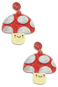 A pair of drop earrings in the shape of smiling mushrooms with glittery red caps and pearly white dots, attached to a matching glittery round charm