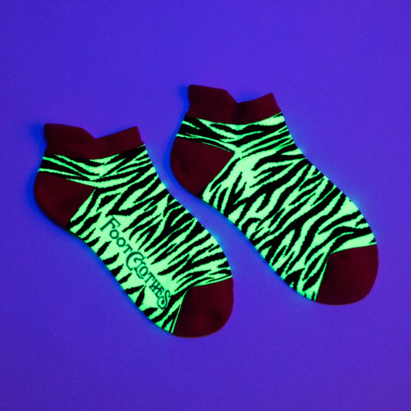 neon yellow and black zebra stripe pattern soft stretch cotton blend ankle socks with neon pink cuffs, heels, and toes. Shown under a blacklight for UV reactive detail