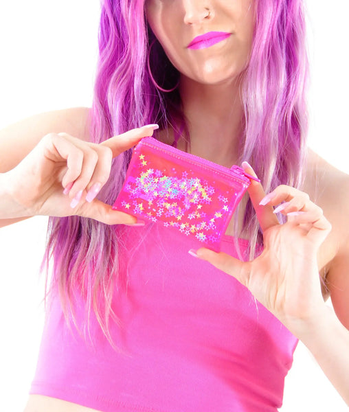 Rectangular neon pink vinyl coin purse with a hot pink plastic zip closure on top. Each side of the purse is filled with clear liquid and has pink, blue, purple, and green star shaped glitter inside. Shown held by a model with both hands
