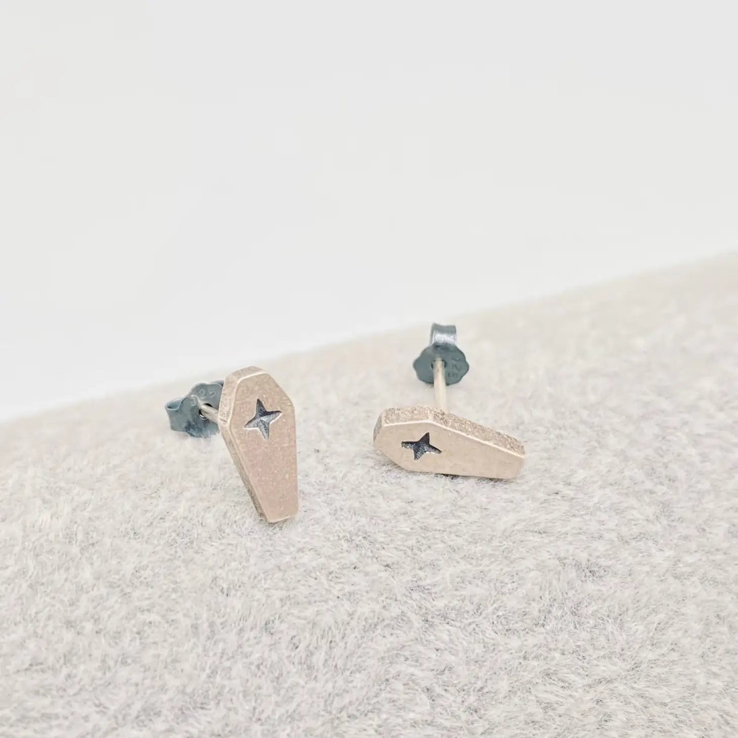 shiny burnished sterling silver coffin shaped post earrings with cross detail. Shown from the front
