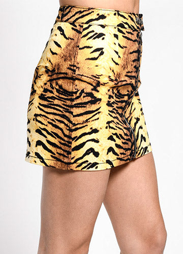 Cotton stretch twill mini skirt in an all-over black, orange, and yellow tiger print. It has a double snap closure at the waistband and a heavy duty silver metal zipper down the front. There is a matching fabric tab with silver metal D-ring on the left hip of the front and back of the skirt. Seen on a model from the side