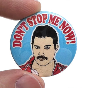 Stylized portrait of Freddie Mercury with the caption “DON’T STOP ME NOW!” in red above on a 1 1/2” round pinback button