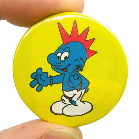 Smurf-like creature with a red Mohawk and spiked bracelets on a yellow background on a 1 1/2” round pinback button