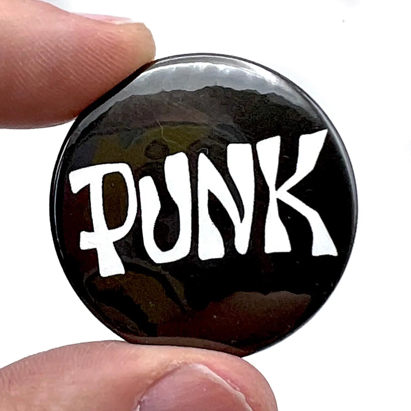 Logo for the 70s zine “PUNK” in white on a black background on a 1 1/2” round pinback button 
