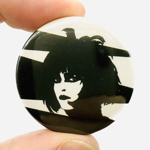 stylized black and white portrait of Siouxsie Sioux against a stark geometric background on a 1 1/2” round plastic pinback button