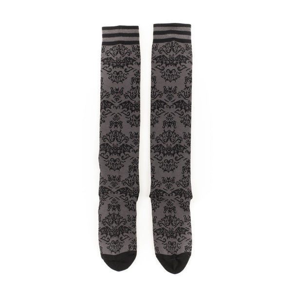 Knee socks with a monochromatic damask pattern of flying bats. Striped grey and black bands at the top of each sock and solid black toes and heels. Shown flat