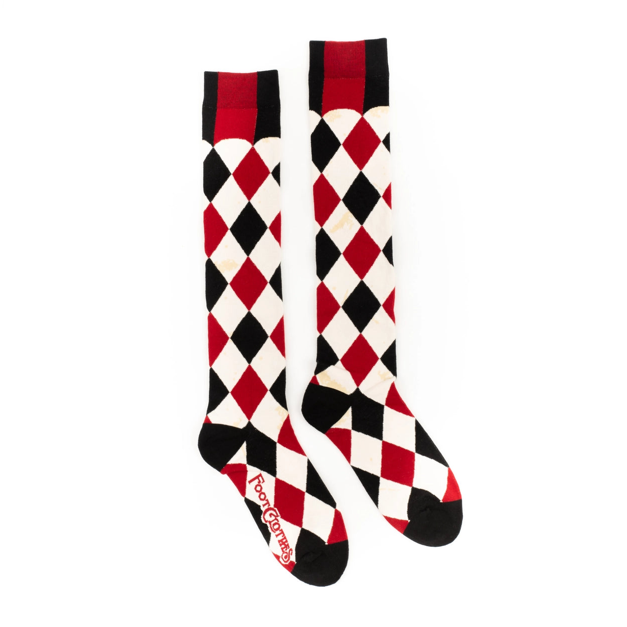 knee socks in a black, red, and cream colored harlequin pattern- with faux-antiqued yellowed age spots throughout each cream colored diamond in the pattern. Shown flat from the side