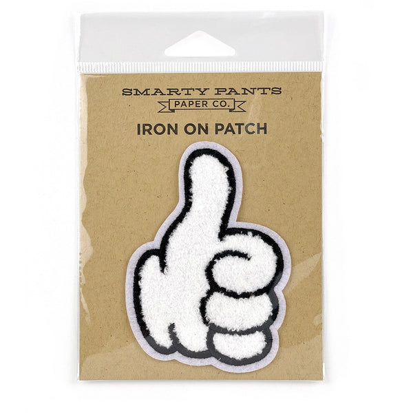 Chenille patch of a white cartoon gloved hand with thick black outline giving a thumbs up. Shown in its cardboard packaging
