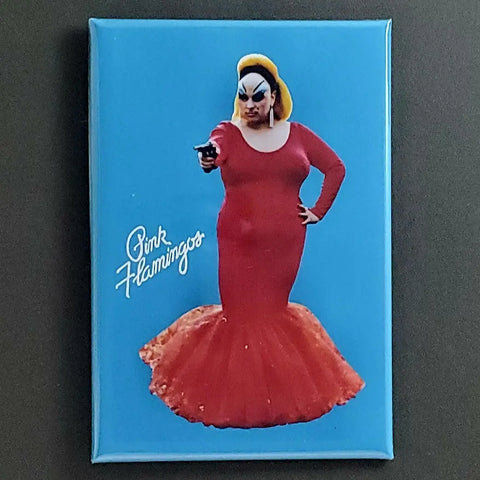 A vertical rectangular magnet featuring a photograph of Divine in a red dress and holding a gun from the 1971 John Waters movie, Pink Flamingos. The title of the movie is written in white script next to the photograph and is on a bright blue background 
