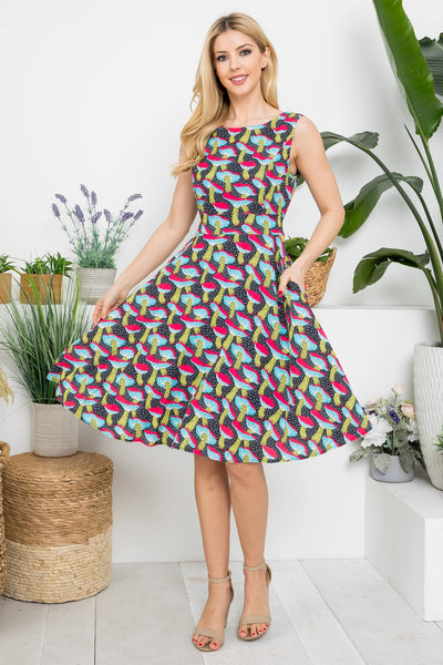 Model wearing black and white dotted background with allover pink, blue, yellow, and red mushroom print sleeveless fit & flare dress with darted bust, self tie belt and pockets. Shown holding skirt wide