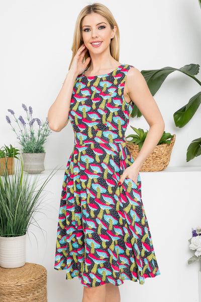 Model wearing black and white dotted background with allover pink, blue, yellow, and red mushroom print sleeveless fit & flare dress with darted bust, self tie belt and pockets. 