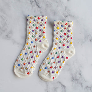 cotton knit socks in white with an allover red, yellow, green, blue, and purple flower knit-in pattern