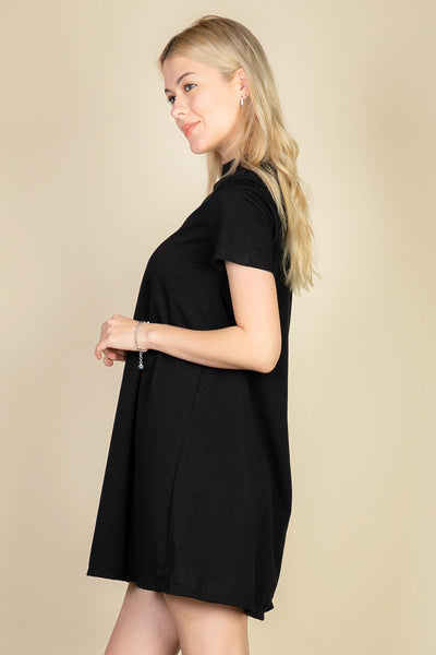 Model wearing a black short sleeved a-line t-shirt mini dress with a high collar. Shown from the side