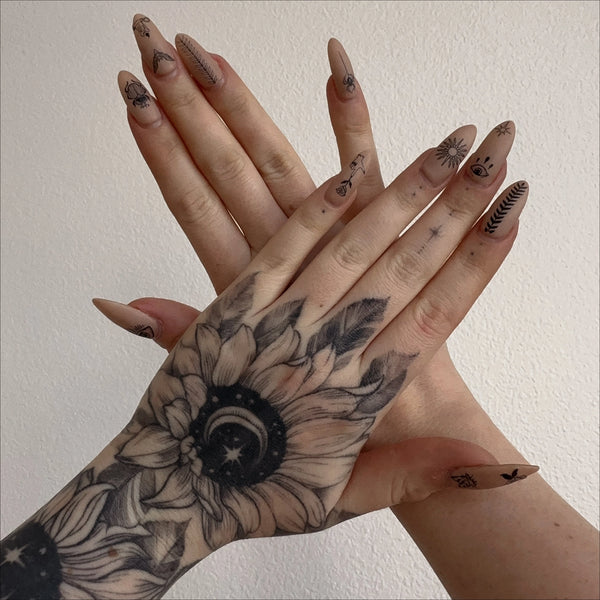 A model with long acrylic nails painted light beige with the nail stickers applied to each nail. Holding their hands out overlapping and straight 