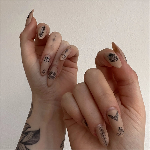 A model with long acrylic nails painted light beige with the nail stickers applied to each nail. Hands are closed with nails facing the camera