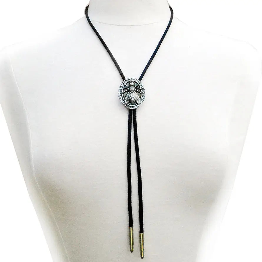 Bolo tie with black cord and silver metal tips with a pendant of a fly on an ornate round plaque